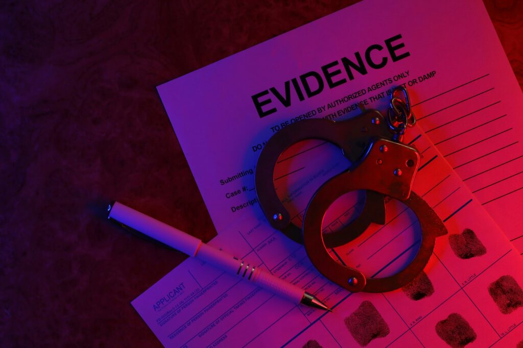 Applicant or fingerprints card with police handcuffs on table in dark room