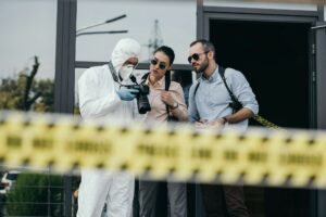 blured police line with detectives and criminologist looking photos on camera on background