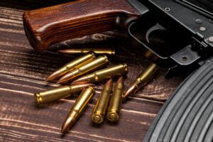 Bullets and Kalashnikov assault rifle on wooden background
