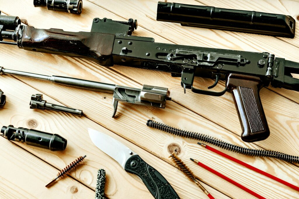 Disassembled rifle with cleaning tools on table of weapons workshop