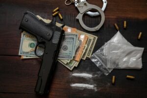 Drugs smuggling and trafficking, Handcuffs, pistol money and cocaine on wooden table background