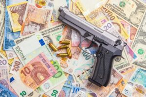 Handgun on various banknotes background. Top view.