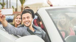 Happy friends making a selfie video streaming in convertible car on summer vacation