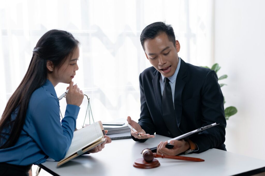 Lawyer and client discussing legal strategy with a gavel and scale of justice in the background.