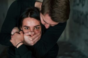 Man's hand covering her mouth. Kidnapped woman is threatened by guy