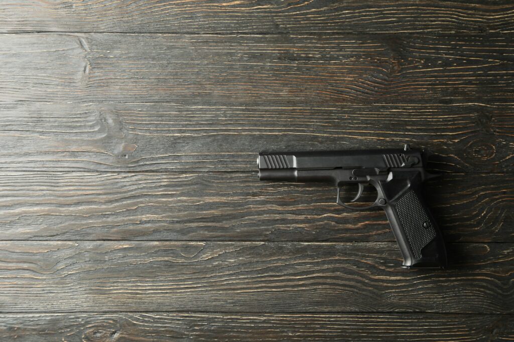 Pistol on wooden background. Self defense weapon