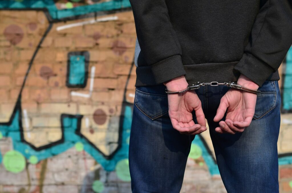 Rear view of the arrested and handcuffed offender against the graffiti background