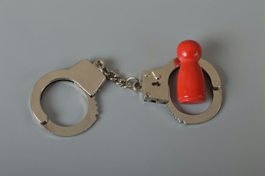 Red wooden people of figure with handcuff locked. Handcuffed convict, law offender and justice