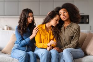 Supporting a friend in distress, three multiracial ladies at home