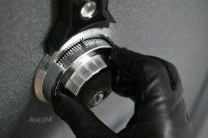 Thief wearing black leather gloves trying to open safe combination lock steal, robbery, crime, theft