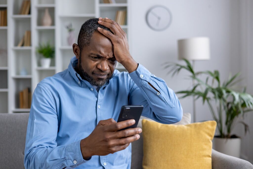 Distressed man discovering fraud on his mobile device