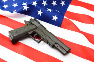 Gun over American patriotic flag, firearms restriction debate.