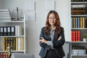 Young lawyer is standing confidently in her office with her arms crossed