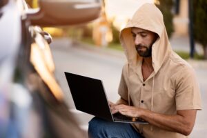 Burglar is trying to steal car using laptop and hacker software. Crime, carjacking concept