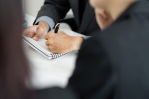 Concentrated note-taking during a business meeting with a professional in a suit.