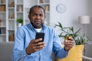 Portrait of a man looking at camera holding credit card and phone