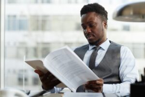 Professional black businessman reading documents at desk in office