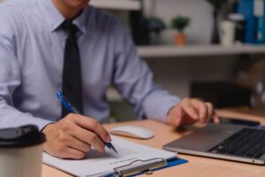 Professional businessman working on contract paperwork with laptop or signing document legal
