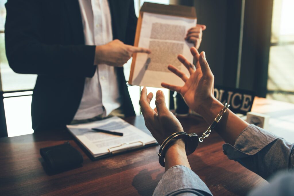 The police officer pointed to the document requesting the arrest of the accused and handcuffed.