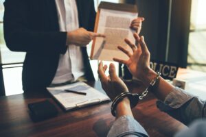 The police officer pointed to the document requesting the arrest of the accused and handcuffed.