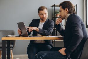 Two successful male partners negotiation project ideas in boardroom.
