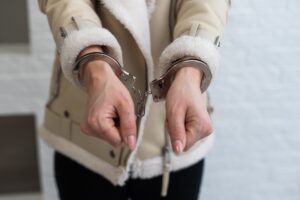 Woman handcuffs in criminal concept. Gray background.