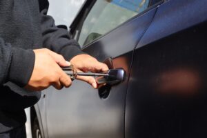 Auto thief trying to break into car with screwdriver.