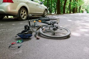 Damaged equipment. Bicycle and silver colored car accident on the road at forest at daytime