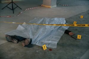 Dead body of a man is on the ground, covered in white cloth. Conception of murder, homicide