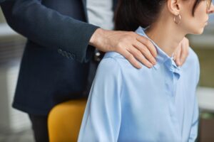 Inappropriate contact in office, male boss rubbing shoulders of young assistant