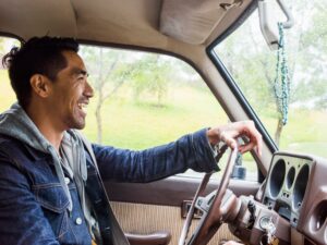 Young man in a car behind the steering wheel, driving.