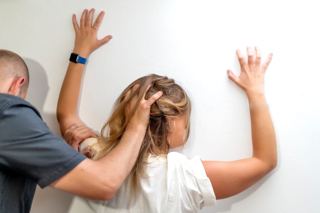 A man mistreating a woman by pulling her hair