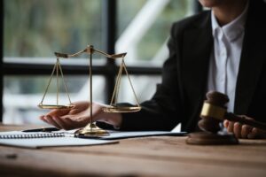 Close up of lawyer's hands and scale of justice on table in the office.
