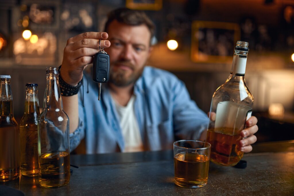 Drunk man with car key sitting at counter in bar
