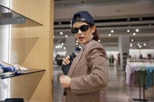 Young female shopaholic thief stealing handbag at shop store