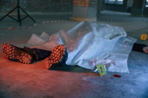 Dead body of a man is on the ground, covered in white cloth. Conception of murder, homicide