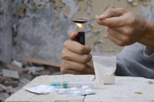 Hands of drug addict melting cocaine in a spoon holds over a cigarette lighter