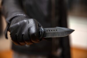 Burglar holding a knife in gloved hand, armed robbery concept.