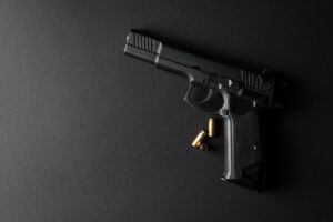 Pistol and traumatic bullets on black background. Self defense weapon