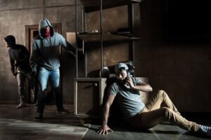 Scared man hiding from burglars breaking indoors, house robbery scene