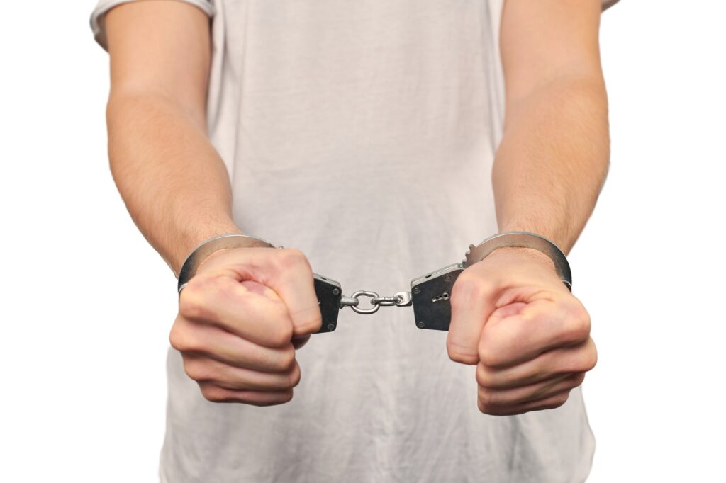 Hands of criminal in handcuffs, arrest of dangerous criminal, violation of law, white background