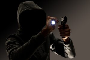 burglary and robbery. skillful professional masked burglar holding a gun and torch and breaking into