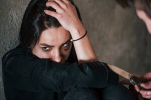 Kidnapped woman sitting and threatened by man with knife in hands in abandoned building