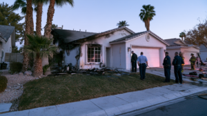 Law enforcement officers and firefighters examining a fire-damaged Nevada home during an arson investigation.